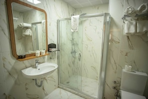 A bathroom with a marble sink, a glass shower enclosure, and a mirror with a wooden frame. - Büyük Mardin Otel (Mardin)