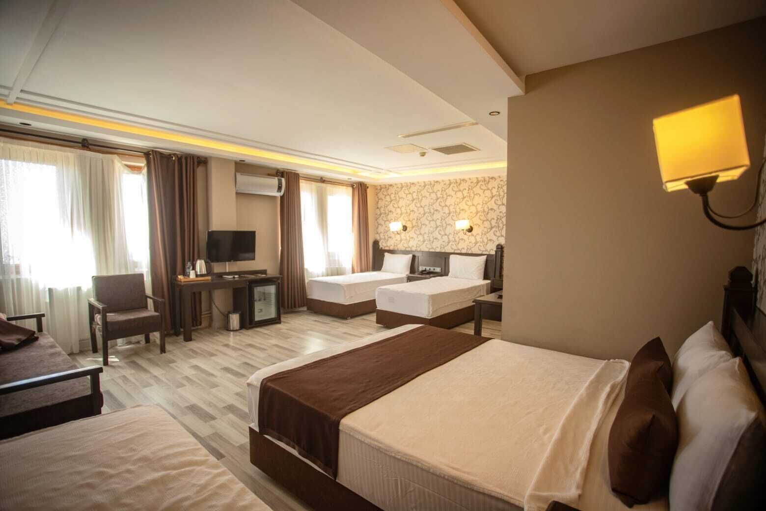 A hotel room with two beds, a desk, a television, and a minibar.