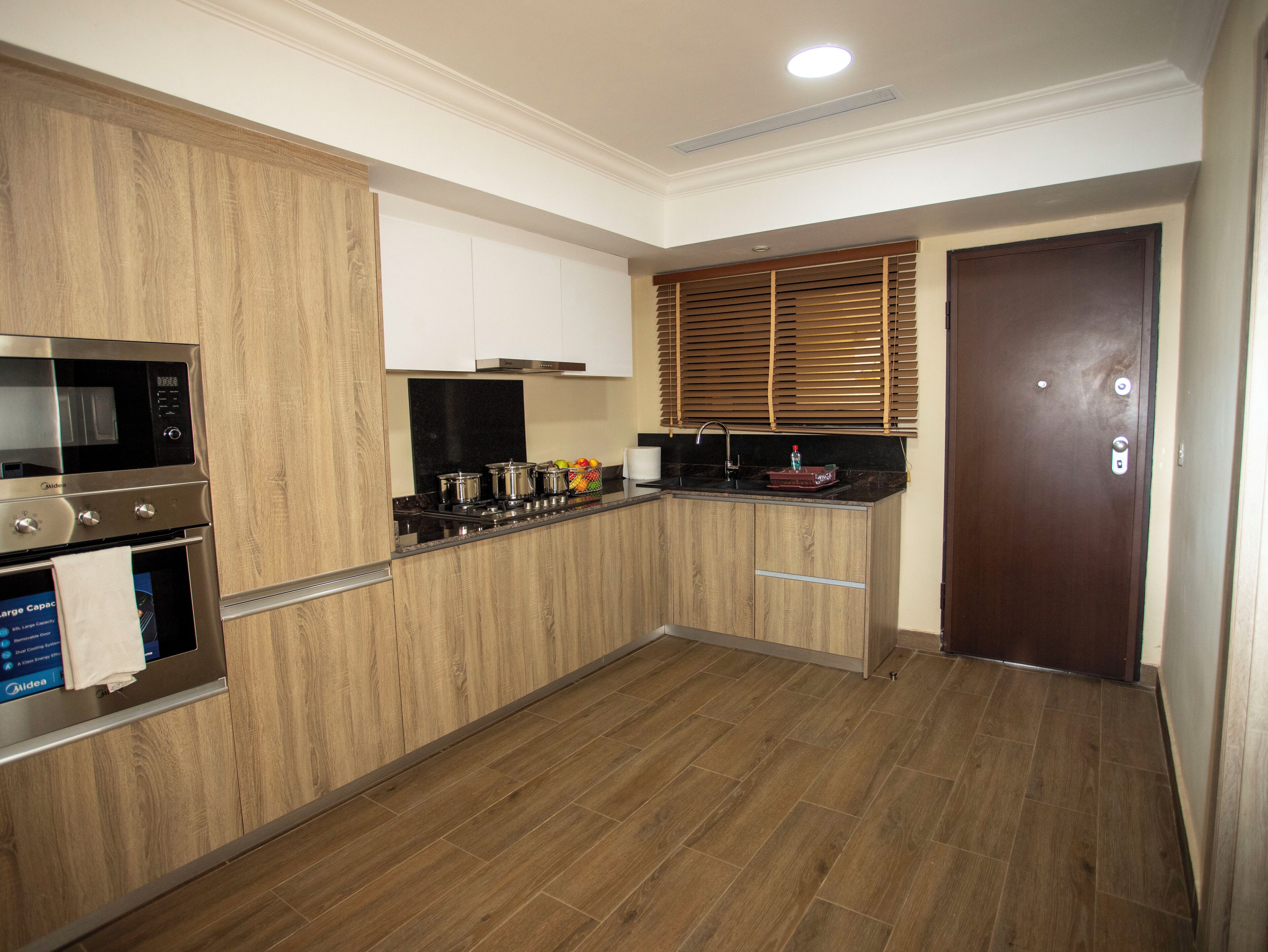 A modern kitchen with wooden cabinetry, a built-in oven, and a microwave.