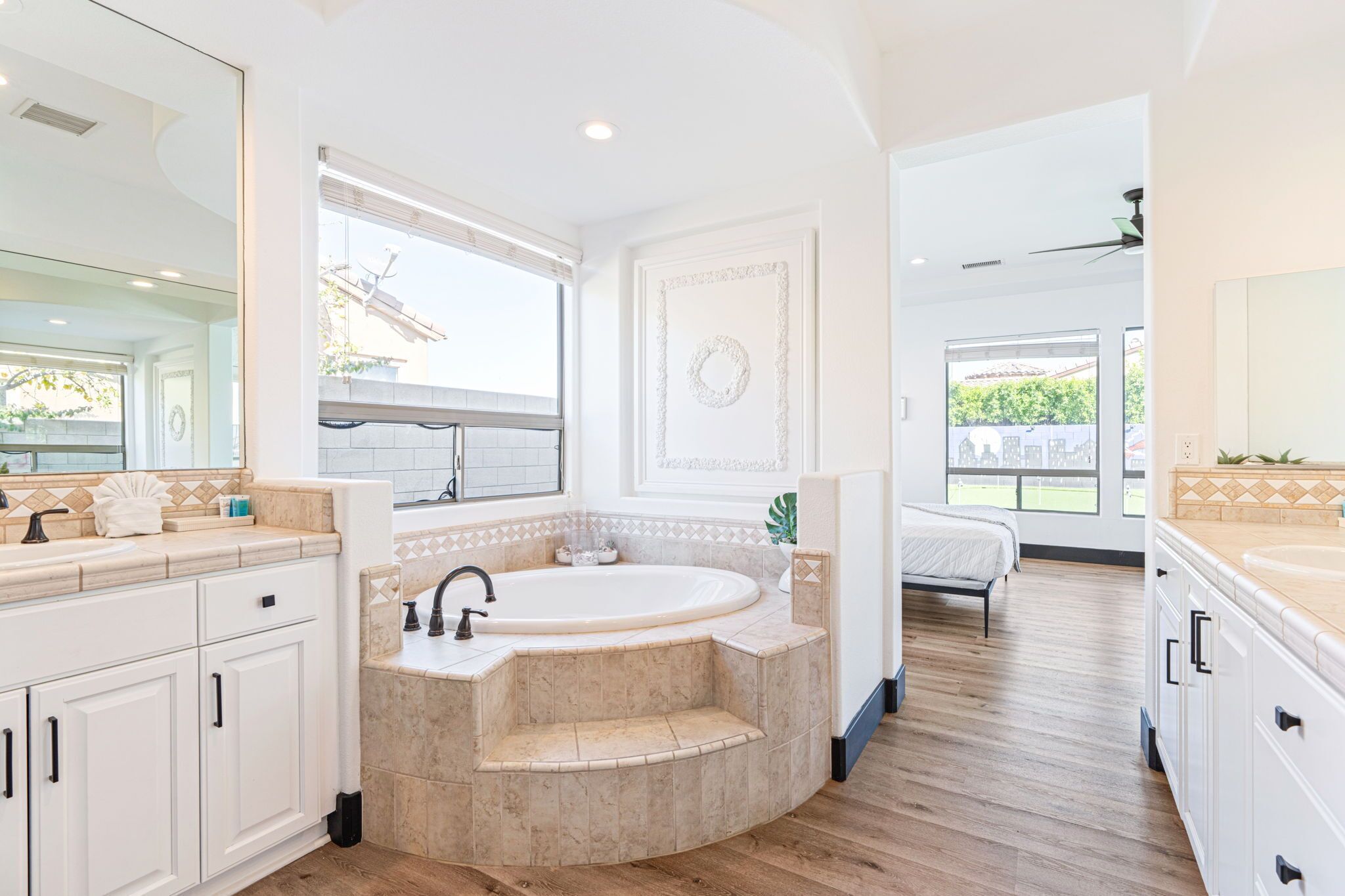 A modern bathroom with a freestanding bathtub, a large mirror, and a window providing a view of the outdoors.