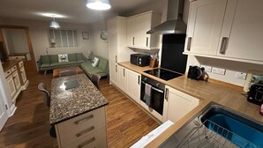 Een kleine keuken met een centraal eiland, een ingebouwde oven en een vaatwasser.