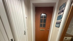 Een hal met houten vloer, witte muren en een deur aan het einde.