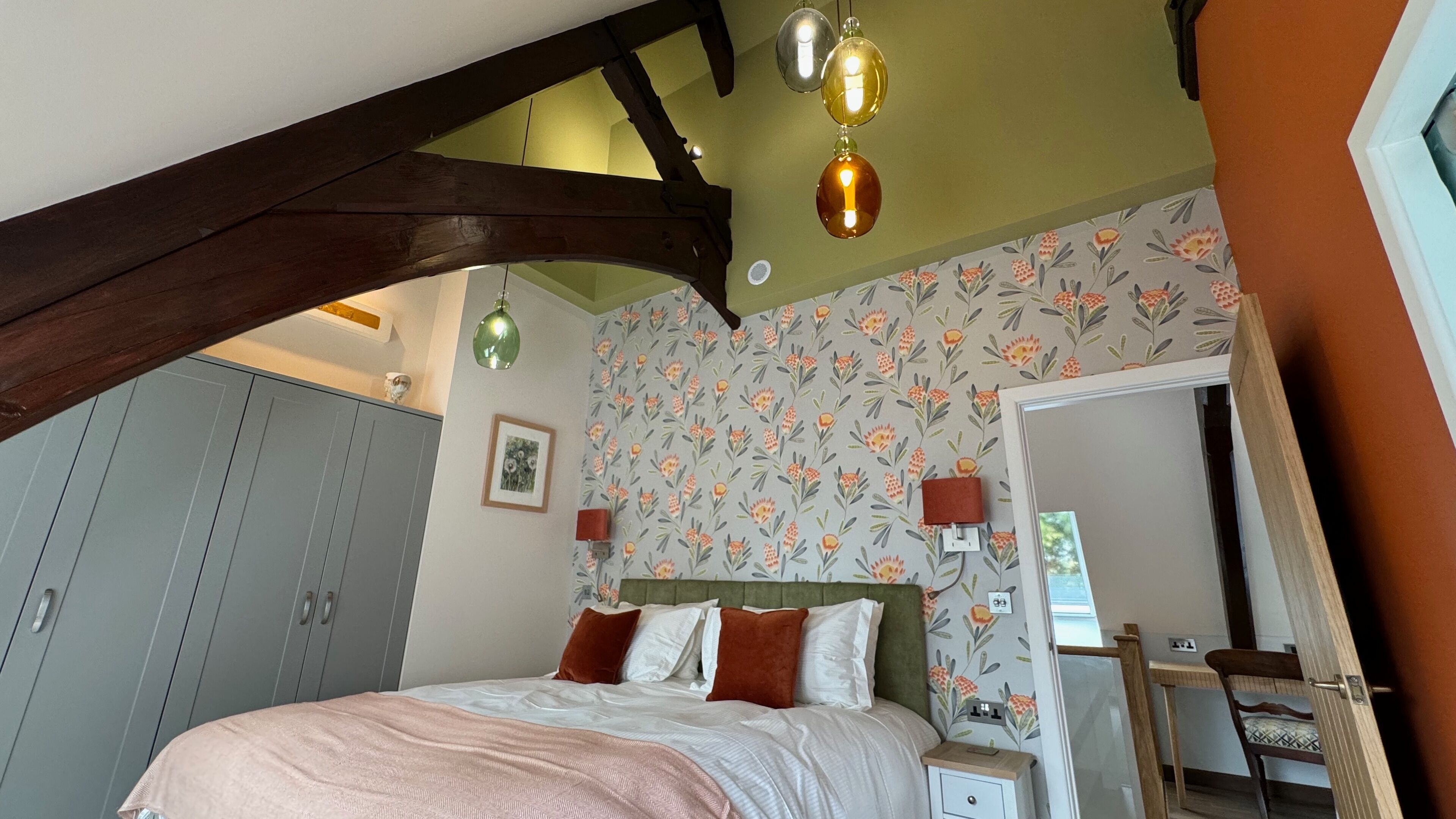 A bedroom with a bed, bedside tables, a wardrobe, and a mirror.