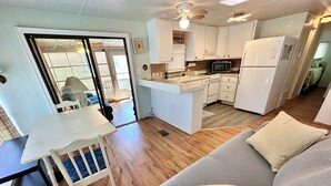 Un espacio habitable compacto con kitchenette, comedor y sofá con cojines.