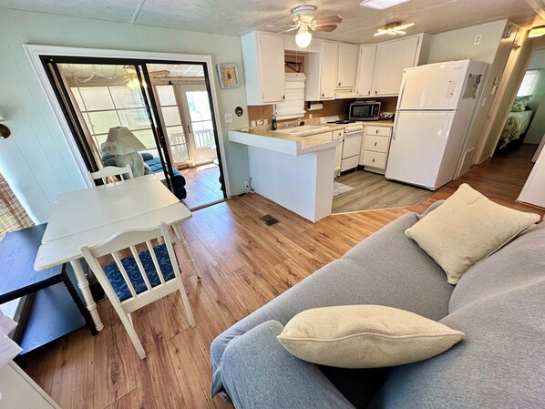 Un espacio habitable compacto con kitchenette, comedor y sofá con cojines.