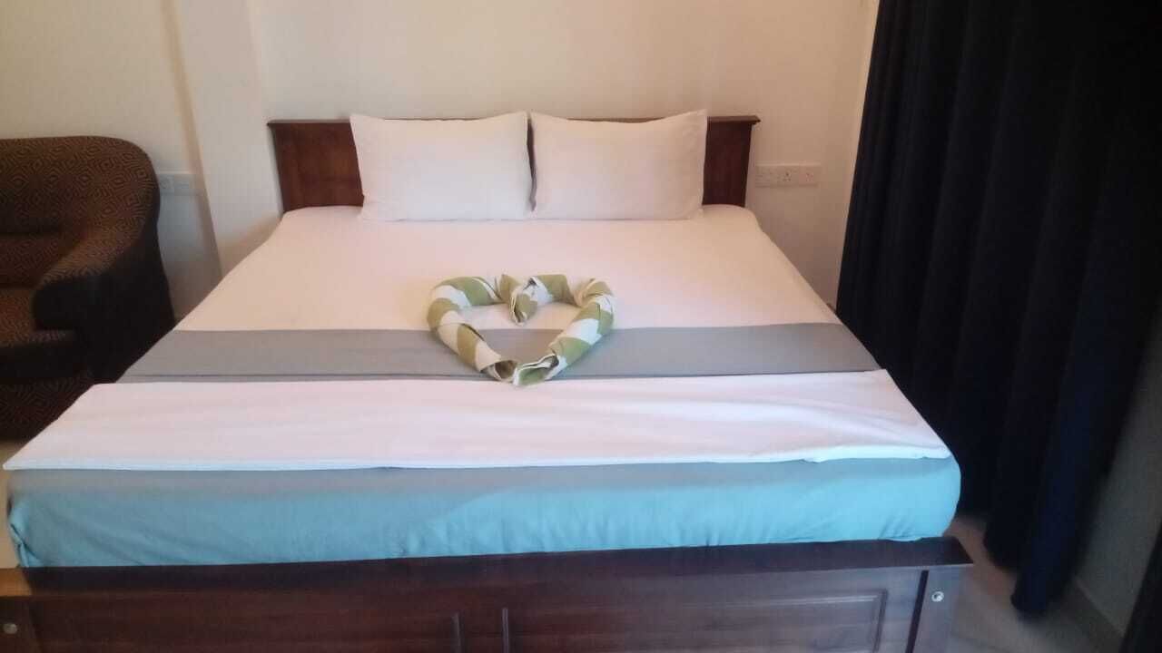 Ein ordentlich bezogenes Bett mit einem herzförmigen Handtuch und einer grauen Bettdecke.