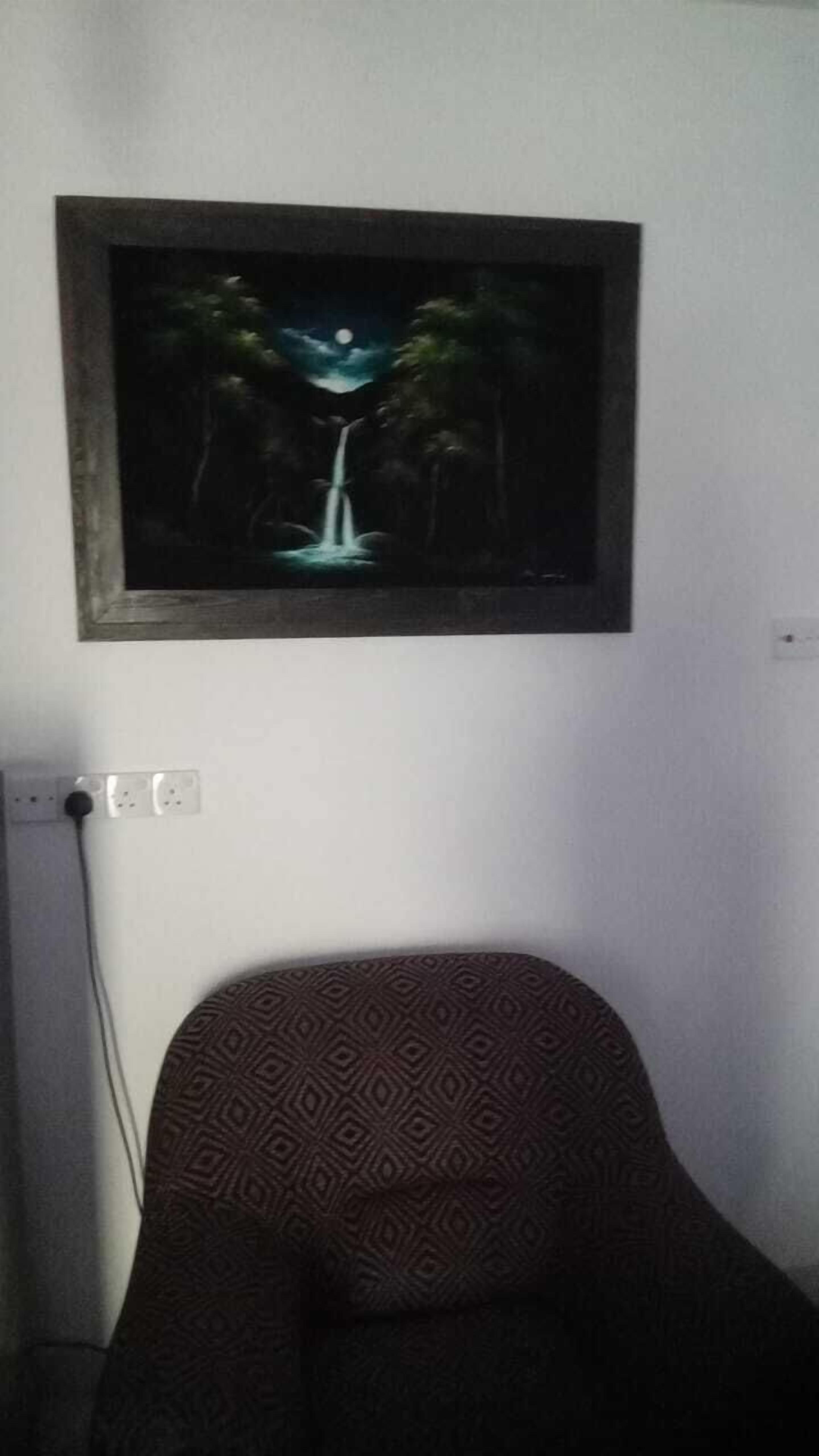 Ein gerahmtes Bild eines Wasserfalls bei Nacht an einer Wand.