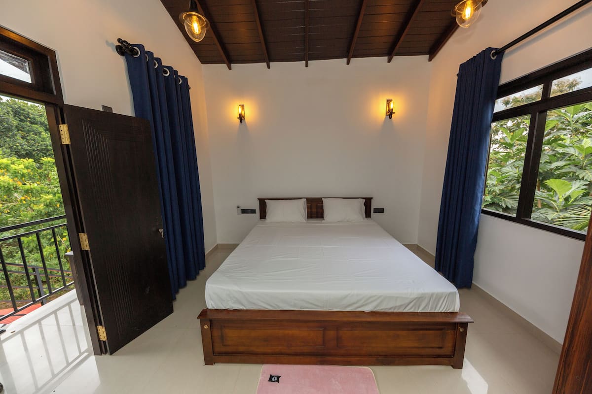 Une chambre à coucher avec un lit en bois, du linge de lit blanc et deux lampes fixées au mur.