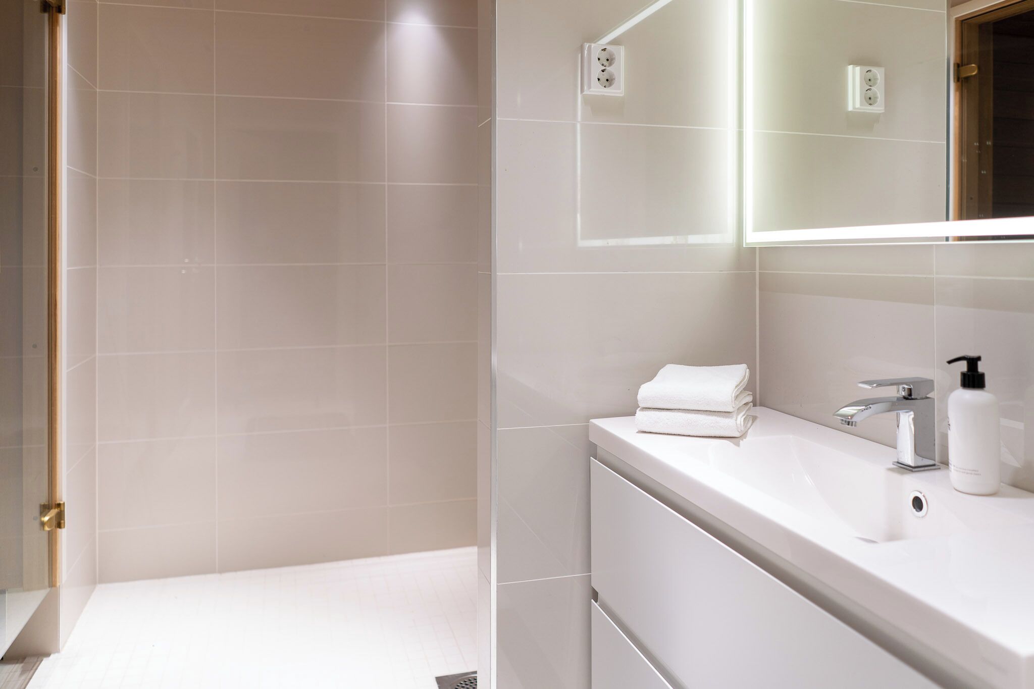 A modern bathroom with a shower, a sink with a mirror, and a towel.