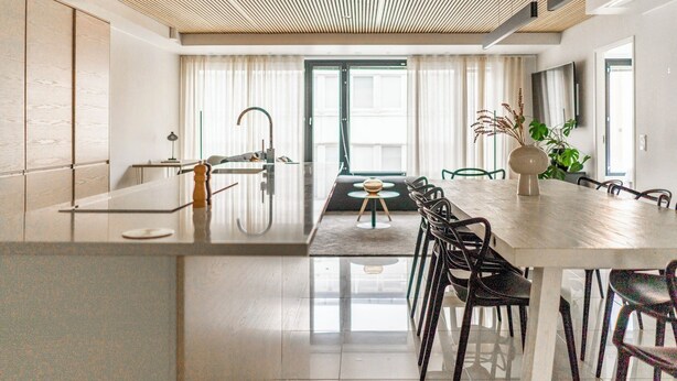 A modern kitchen with a large island, stainless steel appliances, and a dining area with a wooden table and chairs.