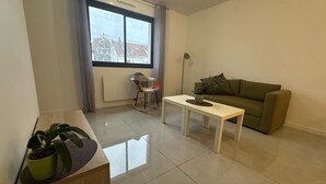 Ein Wohnzimmer mit Sofa, Couchtisch, Schaukelstuhl und Zimmerpflanze.