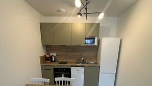 Eine kompakte Küche mit Essbereich. Sie beinhaltet eine Mikrowelle, einen Geschirrspüler und einen Kühlschrank.