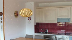 A modern kitchen with white cabinets, a red backsplash, and stainless steel appliances. - Suite Marco Nice Apartment in Cavalese With View (Cavalese)