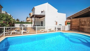 Un edificio moderno, bianco, con piscina e area salotto all'aperto.