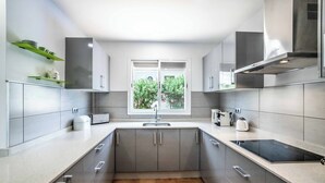 Una cucina moderna con mobili grigi, forno a incasso e una finestra vista verde.