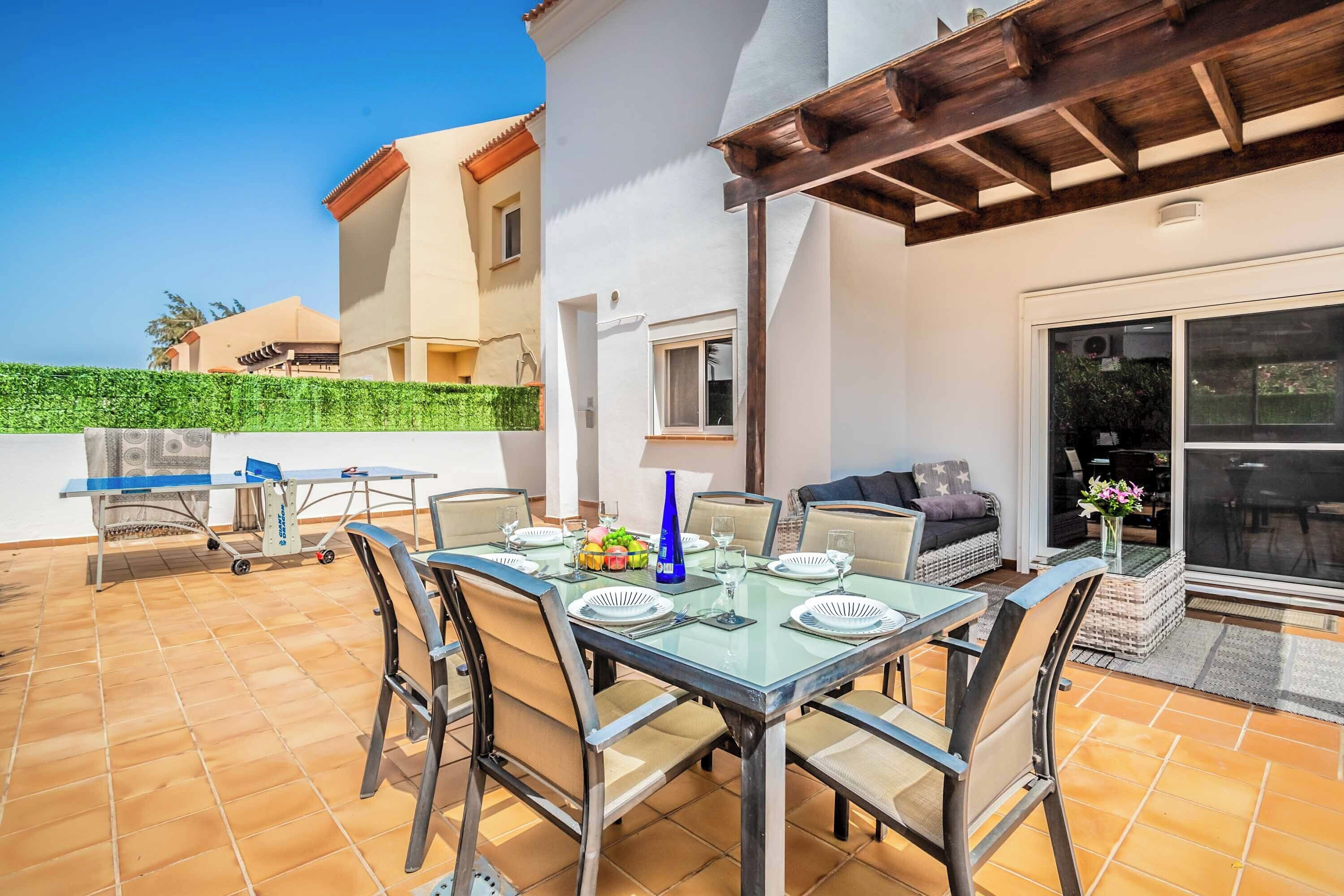 A patio with a dining table set for four, surrounded by chairs.