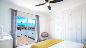 Camera da letto con un letto, una ventola a soffitto, un armadio e vista all'esterno tramite una porta vetrata.
