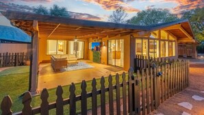 A modern house with a covered patio, large windows, and a wooden fence. - Red Rocks House | Chef`s Kitchen, Fireplace (Sedona)