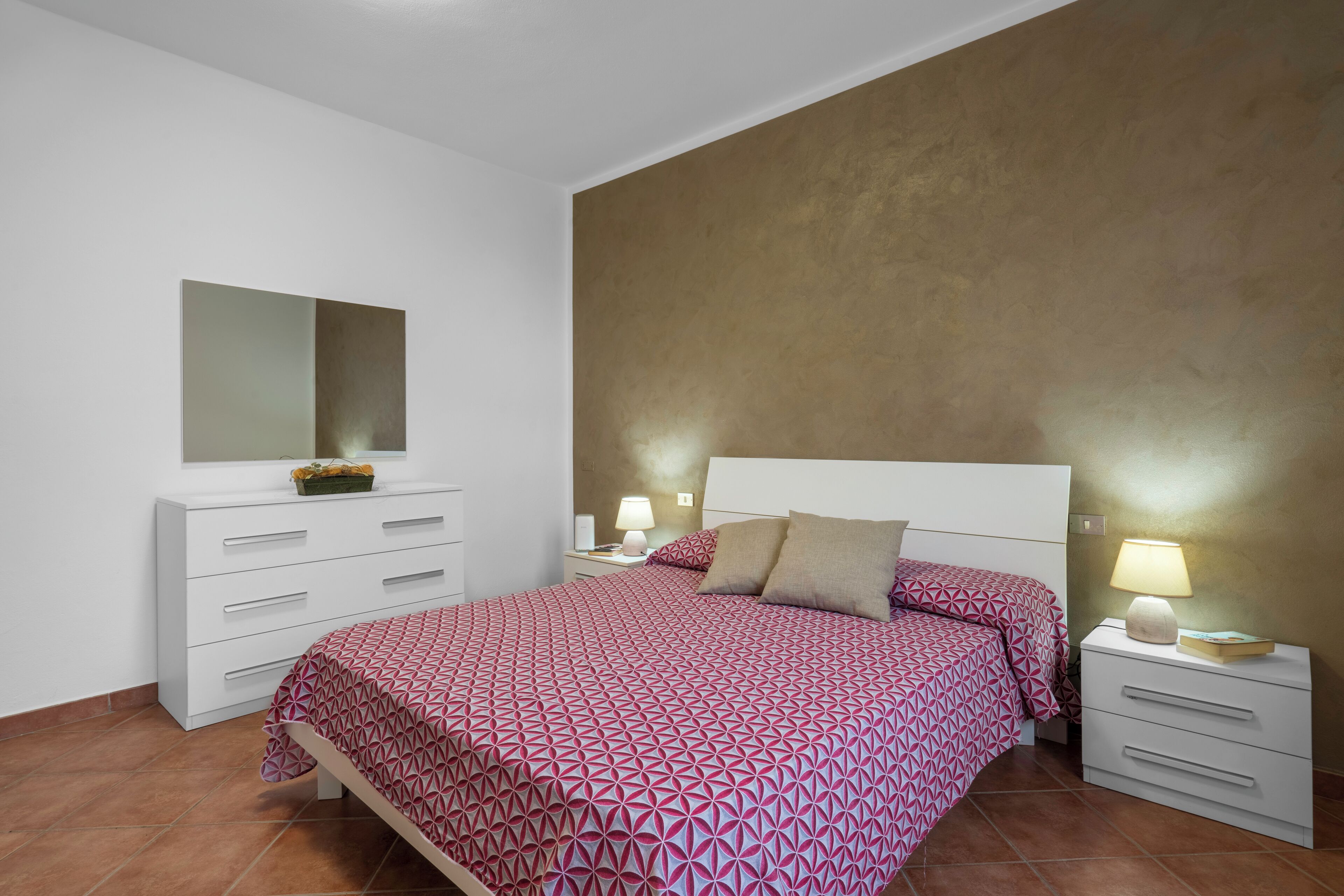 Ein Schlafzimmer mit Bett, Kommode, Nachttisch und Spiegel.