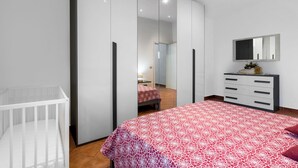A bedroom with a bed, a crib, a dresser, a mirror, and a wardrobe. - Borgo House In Florentine Hills With Pool (Fucecchio)