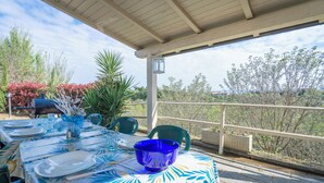 An outdoor dining area with a covered patio, a table set with plates, glasses, and a blue bowl, surrounded by chairs and potted plants. - Borgo House In Florentine Hills With Pool (Fucecchio)