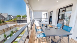 Een balkon met een ontbijttafel, met uitzicht op een woongebied.