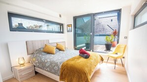 A modern bedroom with a bed, bedside table, and a window overlooking a cityscape. - Luxury villa with indoor pool, 5 minutes from the sea via Groom* (Larmor-Plage)
