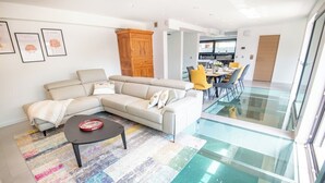 A modern living room with a sectional sofa, a coffee table, and a glass dining area. - Luxury villa with indoor pool, 5 minutes from the sea via Groom* (Larmor-Plage)