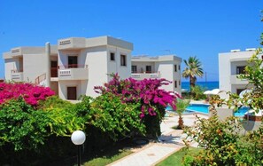 Un resort con varias edificaciones blancas, una piscina y abundante vegetación.