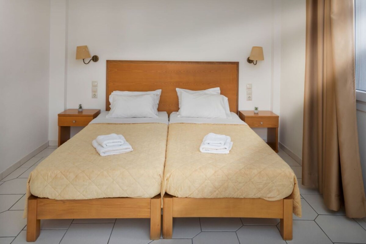 Een hotelkamer met een tweepersoonsbed en twee nachtkastjes, elk met een lamp.