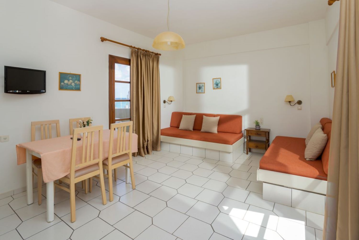 A compact living space with a dining area, a sofa, and a TV mounted on the wall.