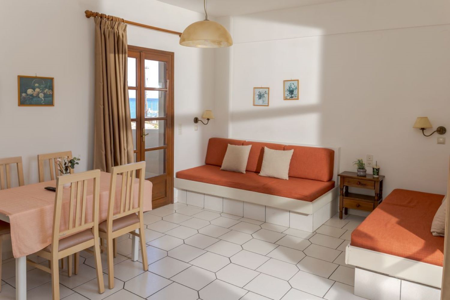 Una habitación con una mesa de comedor, sillas, un sofá, una mesita de noche y una lámpara.