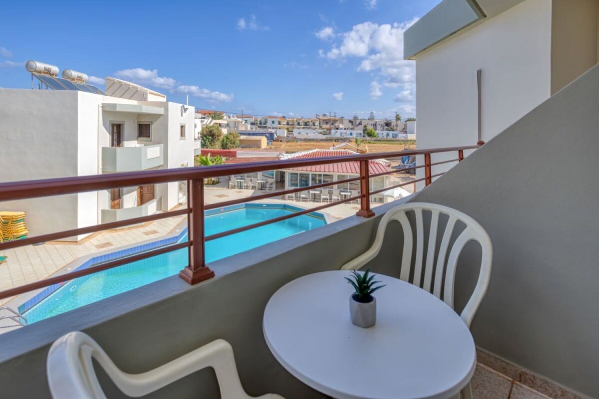 Ein Balkon mit Pool, weißen Stühlen und einem kleinen Tisch.