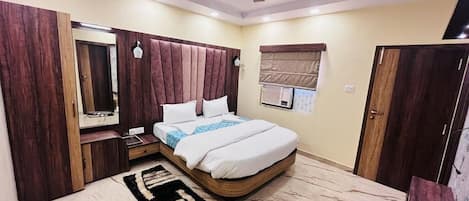 Een slaapkamer met een bed, een plafondventilator, een kledingkast, een spiegel en een raam met jaloezieën.
