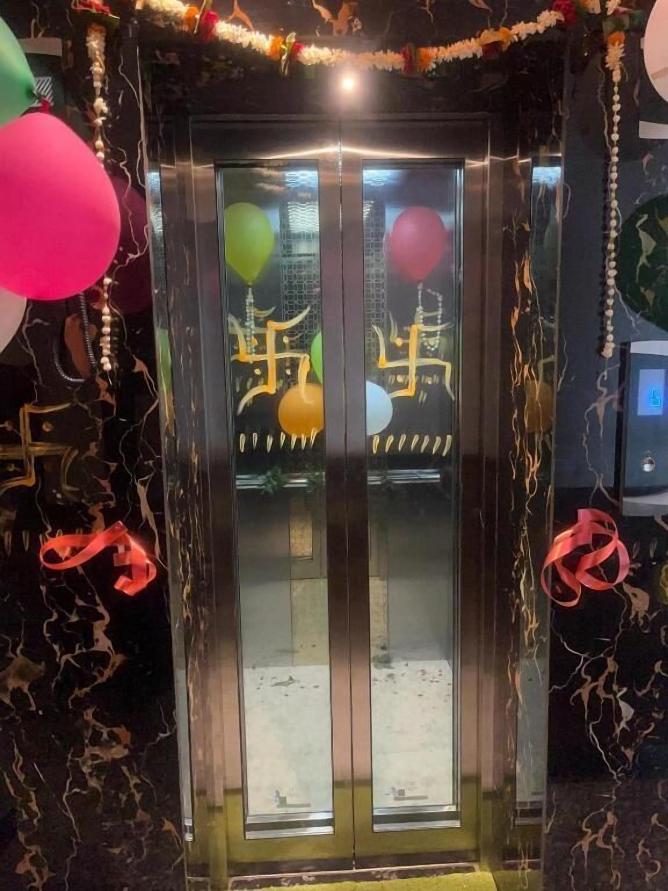 A glass elevator door with festive decorations and balloons.