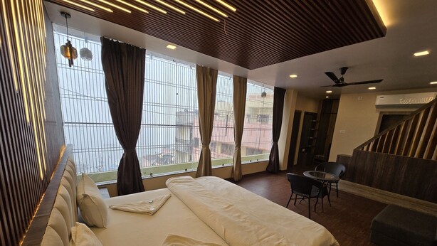 Habitación de hotel con una cama grande, un escritorio y una silla. Cuenta con ventanas con cortinas, un ventilador de techo y vistas al exterior.
