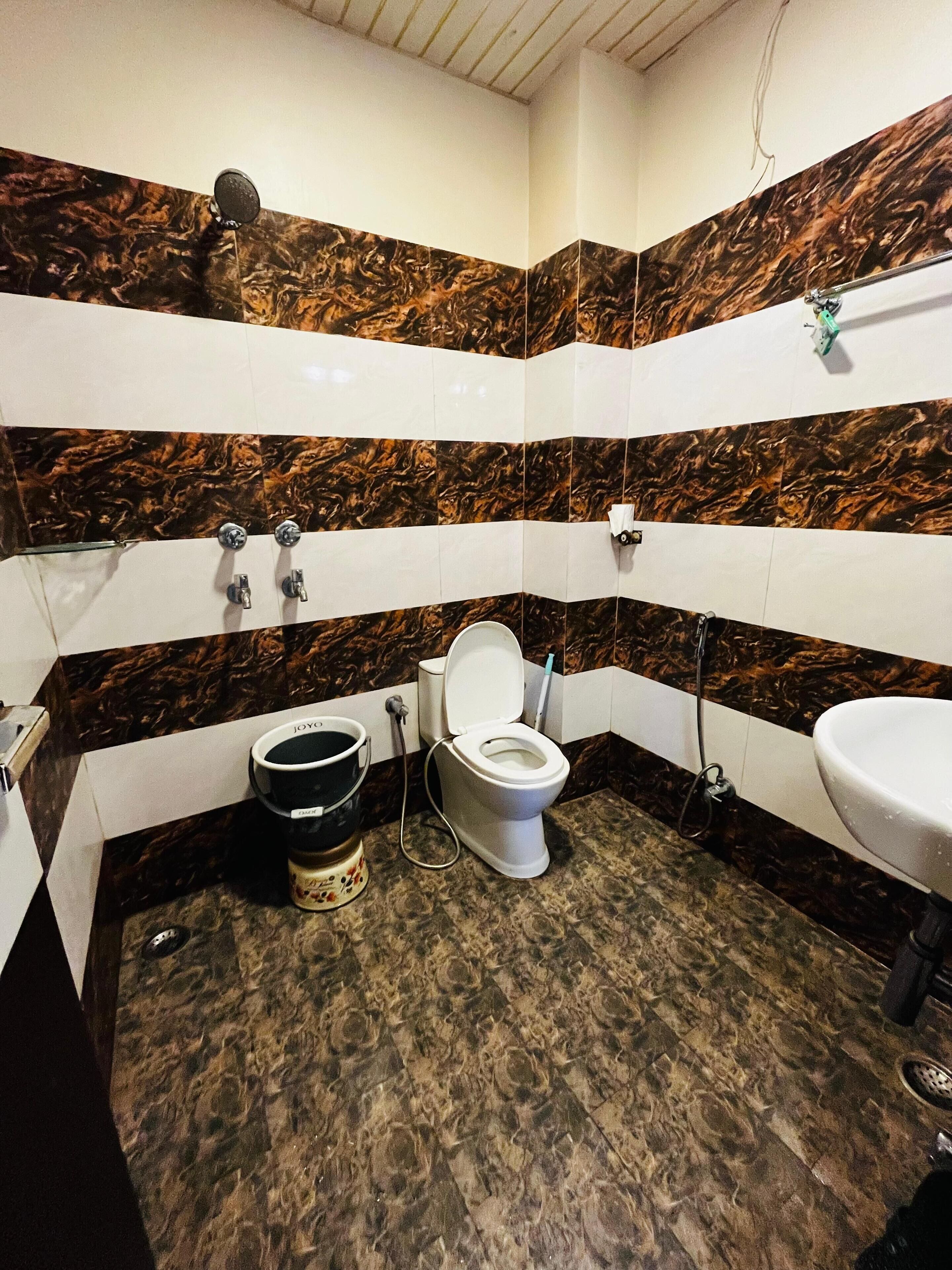 A bathroom with a toilet, sink, and shower. The walls have a marble-like pattern.