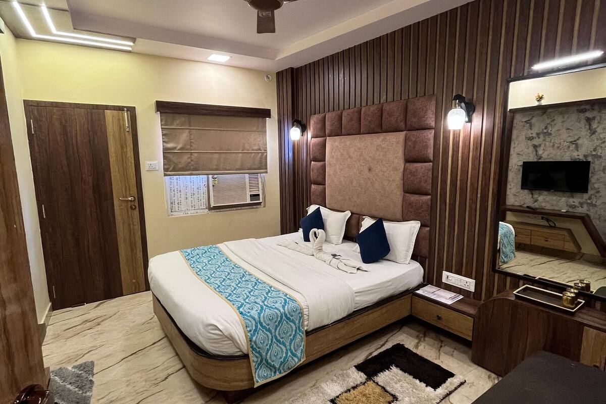 A modern bedroom with a large bed, a ceiling fan, a TV, and a marble floor.