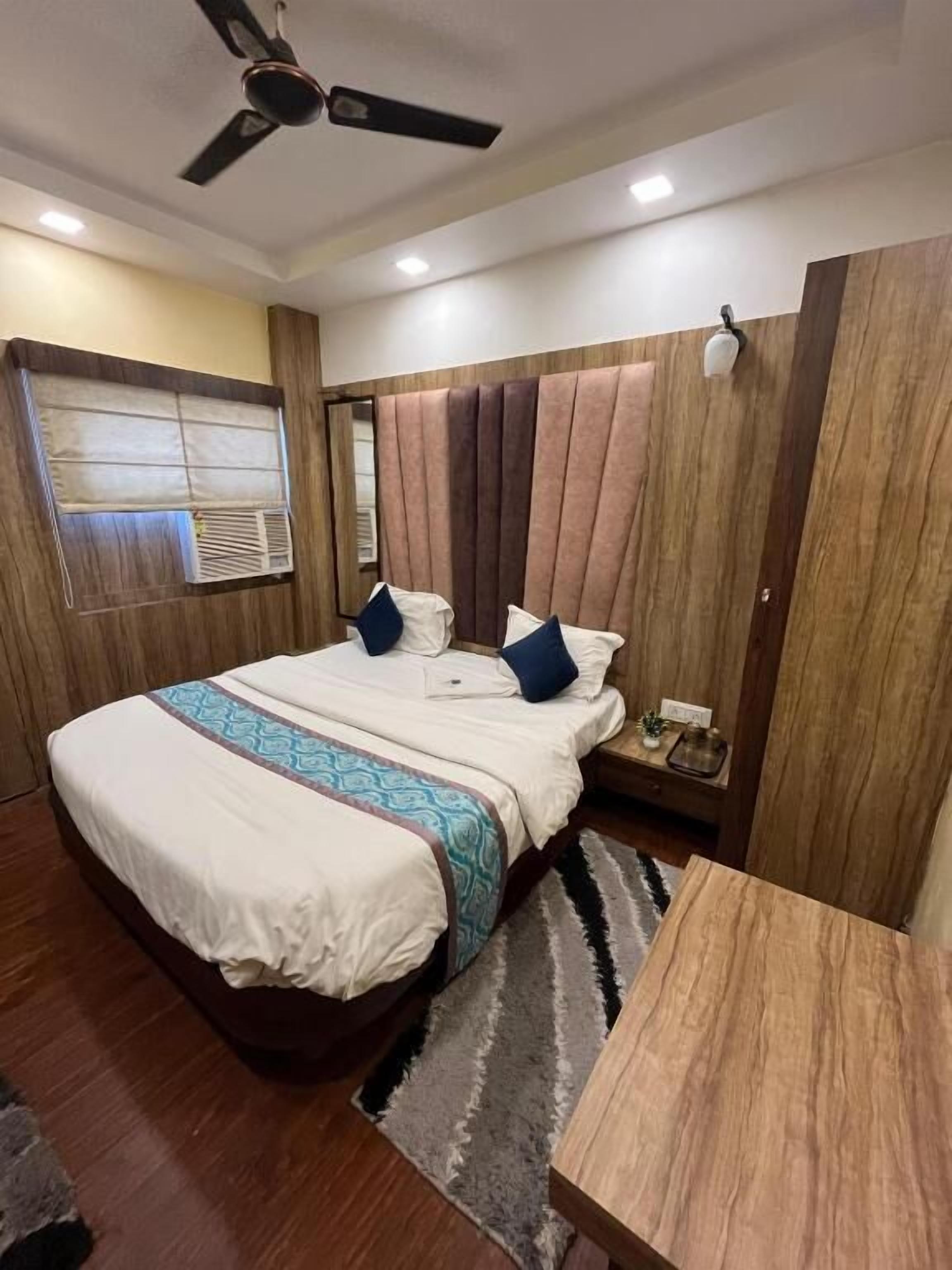 Een slaapkamer met een bed, nachtkastje en plafondventilator.