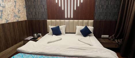 A modern hotel room with a large bed, wooden panel ceiling, and patterned wall tiles.