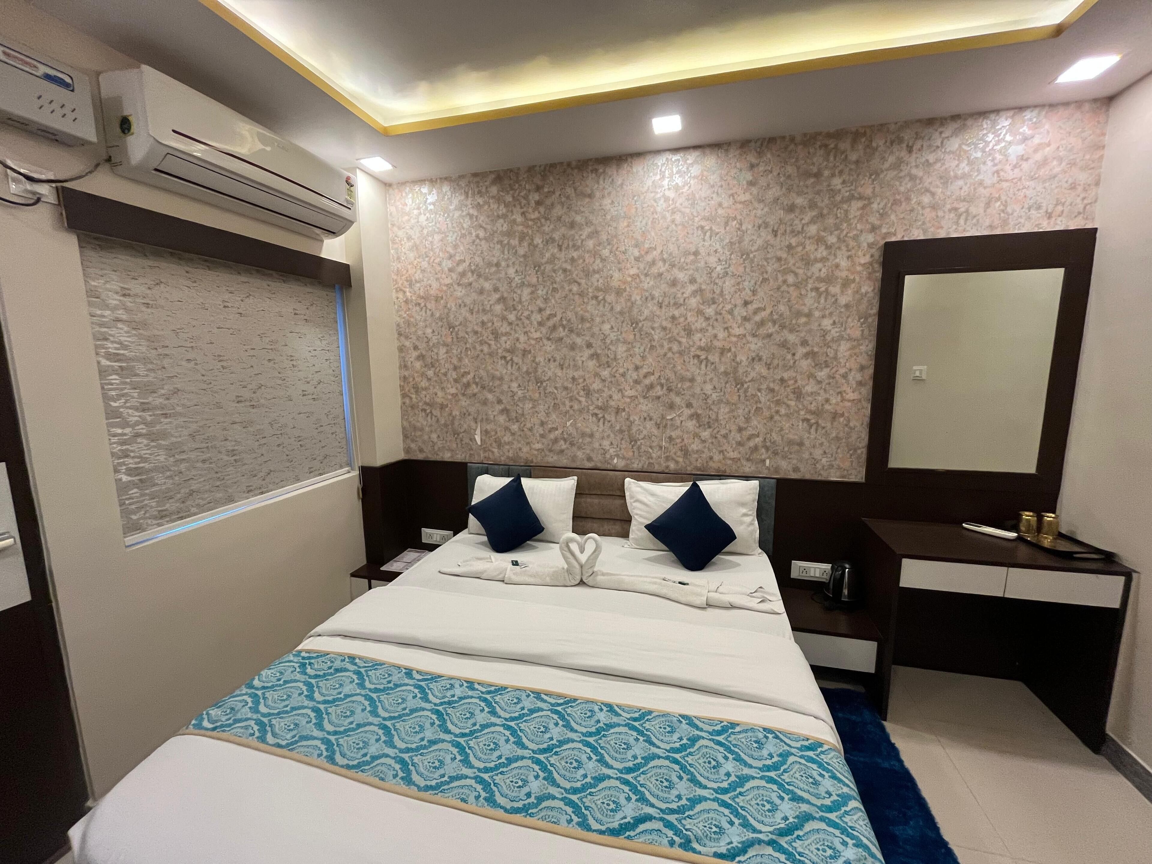Una habitación de hotel con una cama, mesita de noche y espejo.
