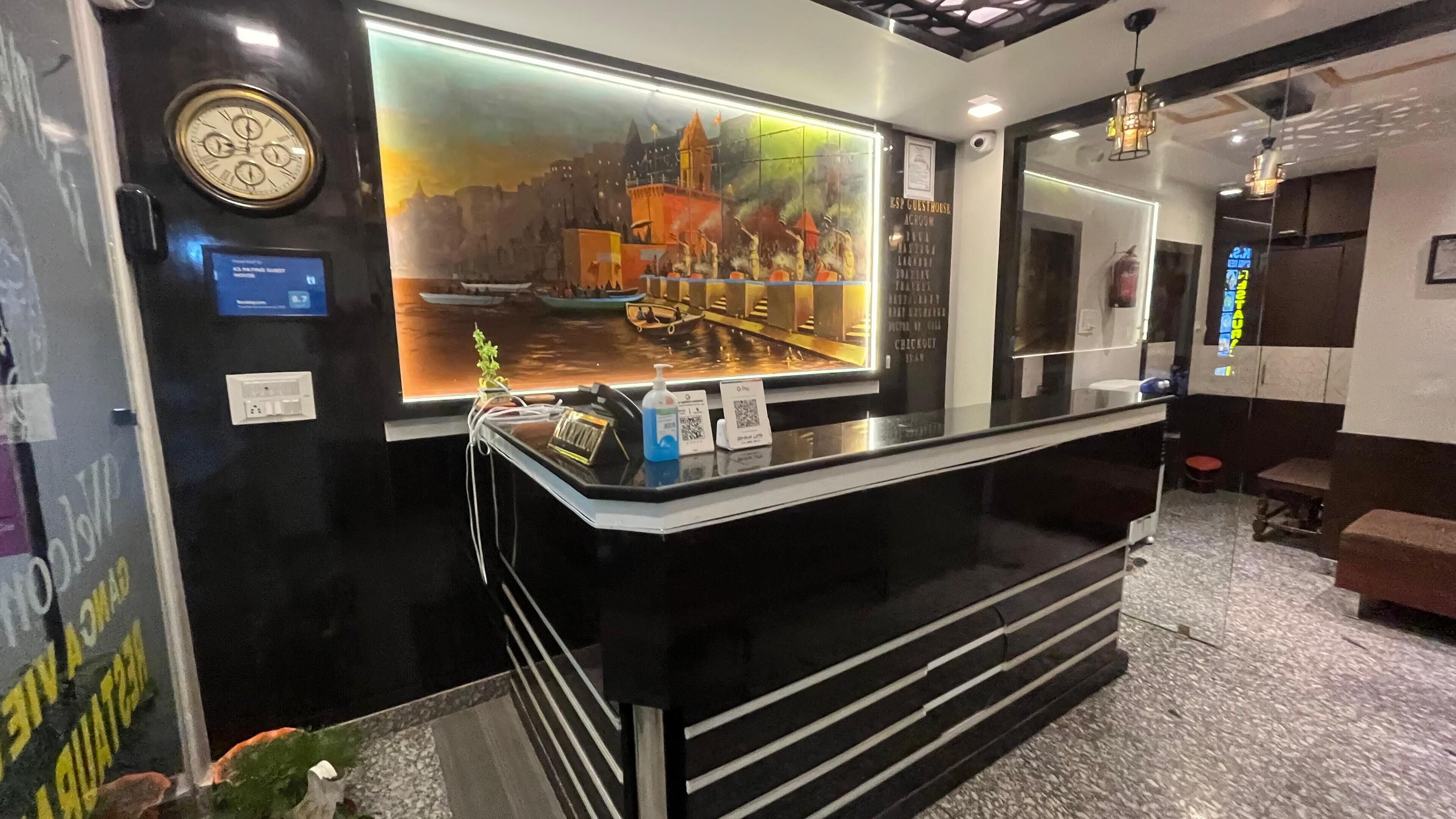 A reception desk with a large digital display of a cityscape, a clock, and a QR code for check-in.