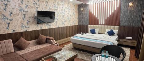 A modern living room with a sofa set, a coffee table, a dining area with chairs, and a bed with a headboard.