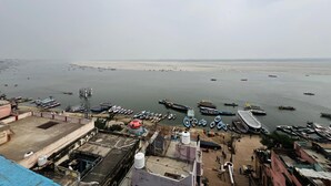 Vista a la orilla del río con barcos amarrados, un puente y edificios de techo plano.