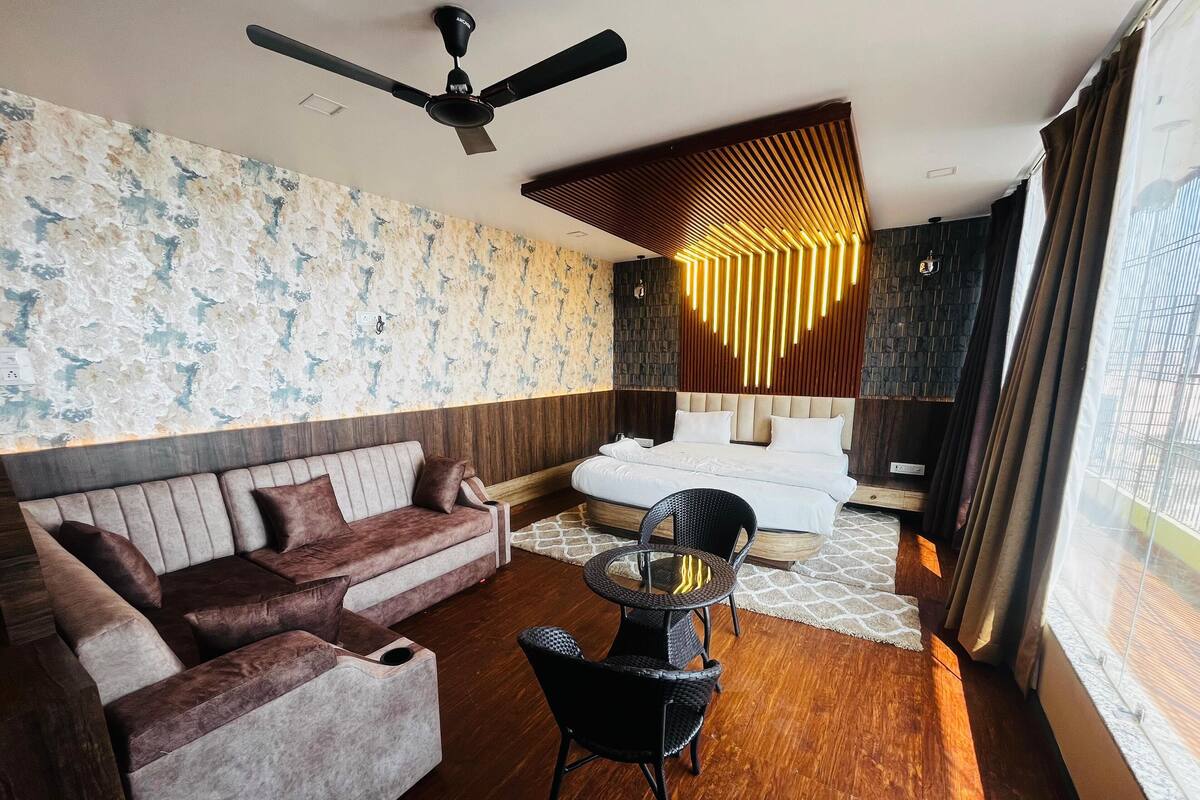 A modern hotel room with a sofa, a round table, and a bed.
