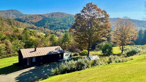Une propriété située en zone rurale, comprenant un bâtiment d’un seul étage, une pelouse bien entretenue et une vue sur des collines ondoyantes.