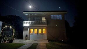 A two-story house with a balcony, a front door with glass panels, and a visible staircase leading to the upper floor. - First Floor Unit with big patio. Countryside steps away from beautiful beaches. (Cabo Rojo)