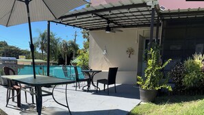 An outdoor patio with a table and chairs, a barbecue grill, and a swimming pool. - First Floor Unit with big patio. Countryside steps away from beautiful beaches. (Cabo Rojo)