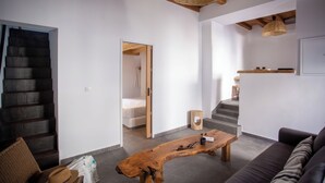 A modern living room with a wooden coffee table, a sofa, a wicker ceiling light, and a staircase leading to another room. - The pelican heritage house, Rooftop Chora Mykonos center (mykonos)