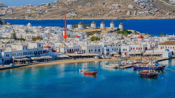 A coastal town with white buildings, a harbor with boats, and windmills in the background. - The pelican heritage house, Rooftop Chora Mykonos center (mykonos)